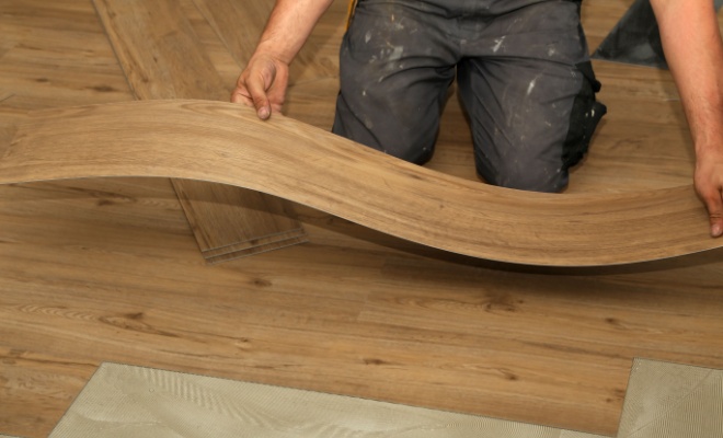 hands holding flexible piece of vinyl flooring