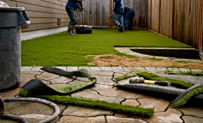 artificial grass being installed in a small garden