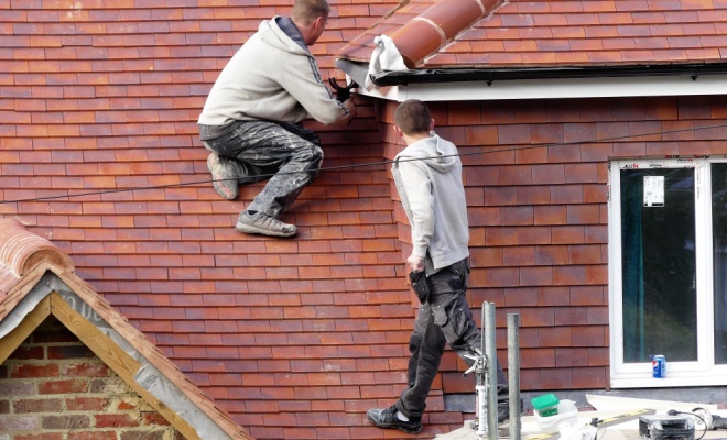 Two men on ladders fitting new guttering