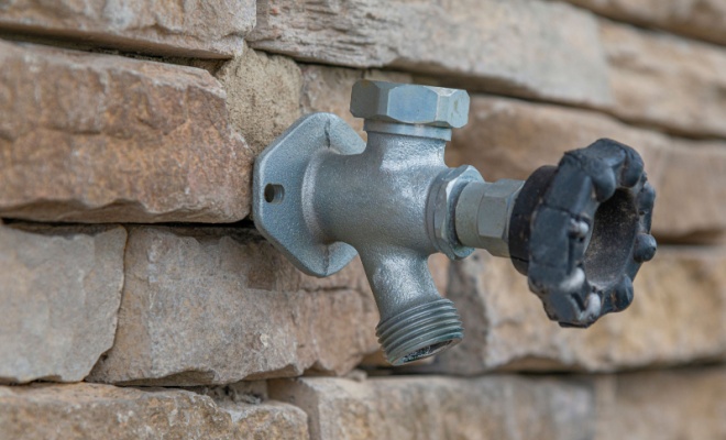 close up of metal tap on stone wall