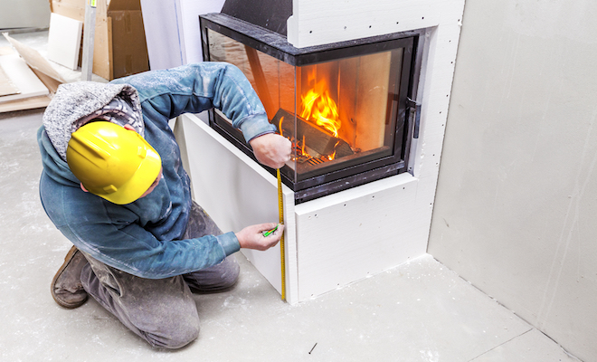 person measuring a firepalce with tape measure