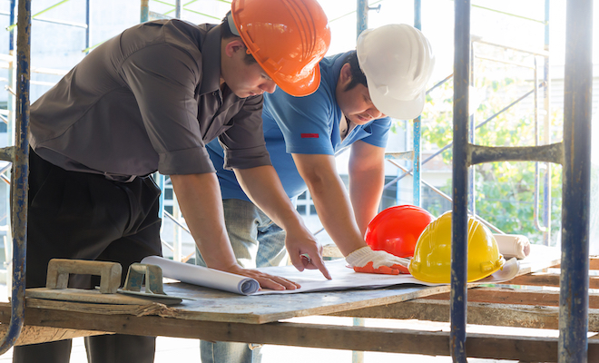 two men in hard hat looking at plans