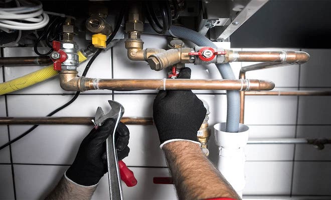 tradesperson servicing underneath a boiler