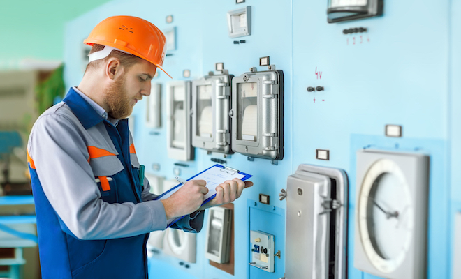 man in orange hard hat making notes