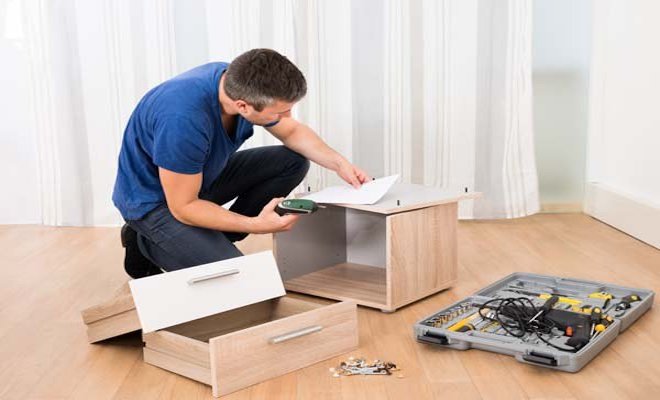 man assembling a small chest of drawers