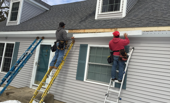 Two men on ladders fitting new guttering