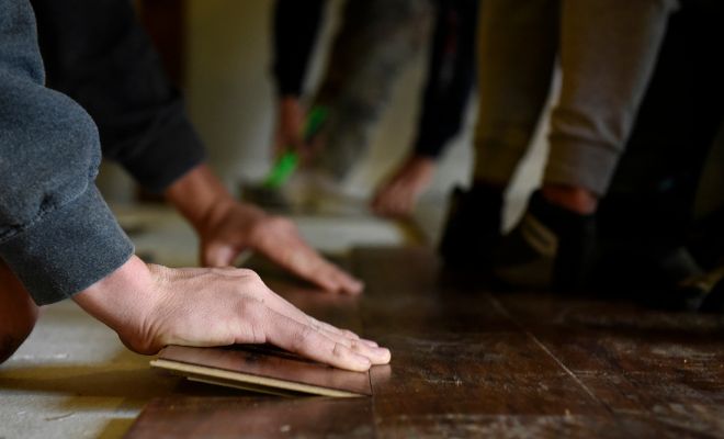hands putting dark wood flooring into place