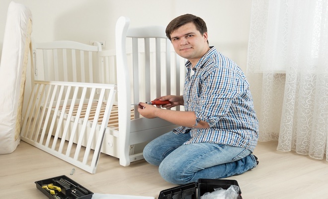 man putting together a white cot