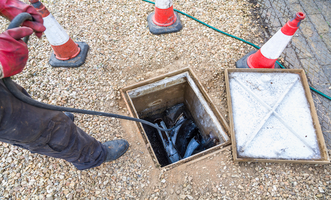 person clearing a blocked drain