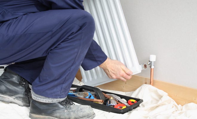 Tradesperson removing radiator off the wall
