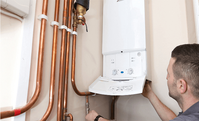 man checking boiler with lots of pipes nearby