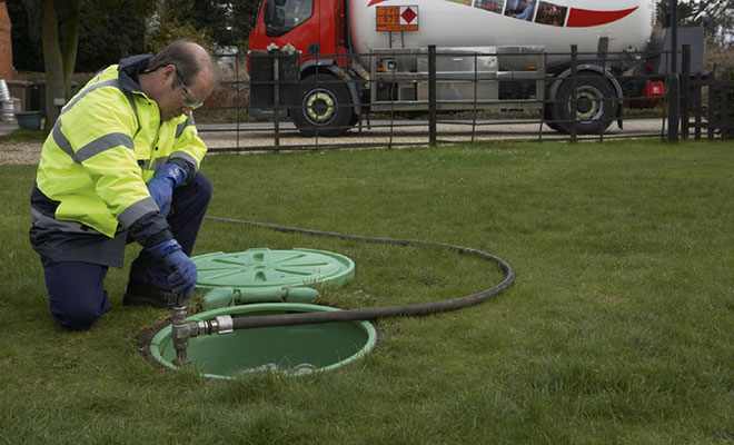 workman refilling underground lpg tank