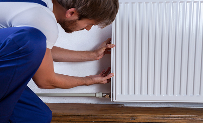 man replacing a radiator in blue overalls