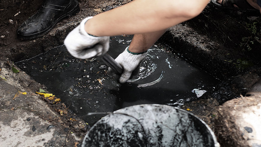 person unblocking outside drain